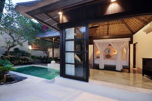 A poolside area with a glass door leading to a bedroom with a canopy bed.