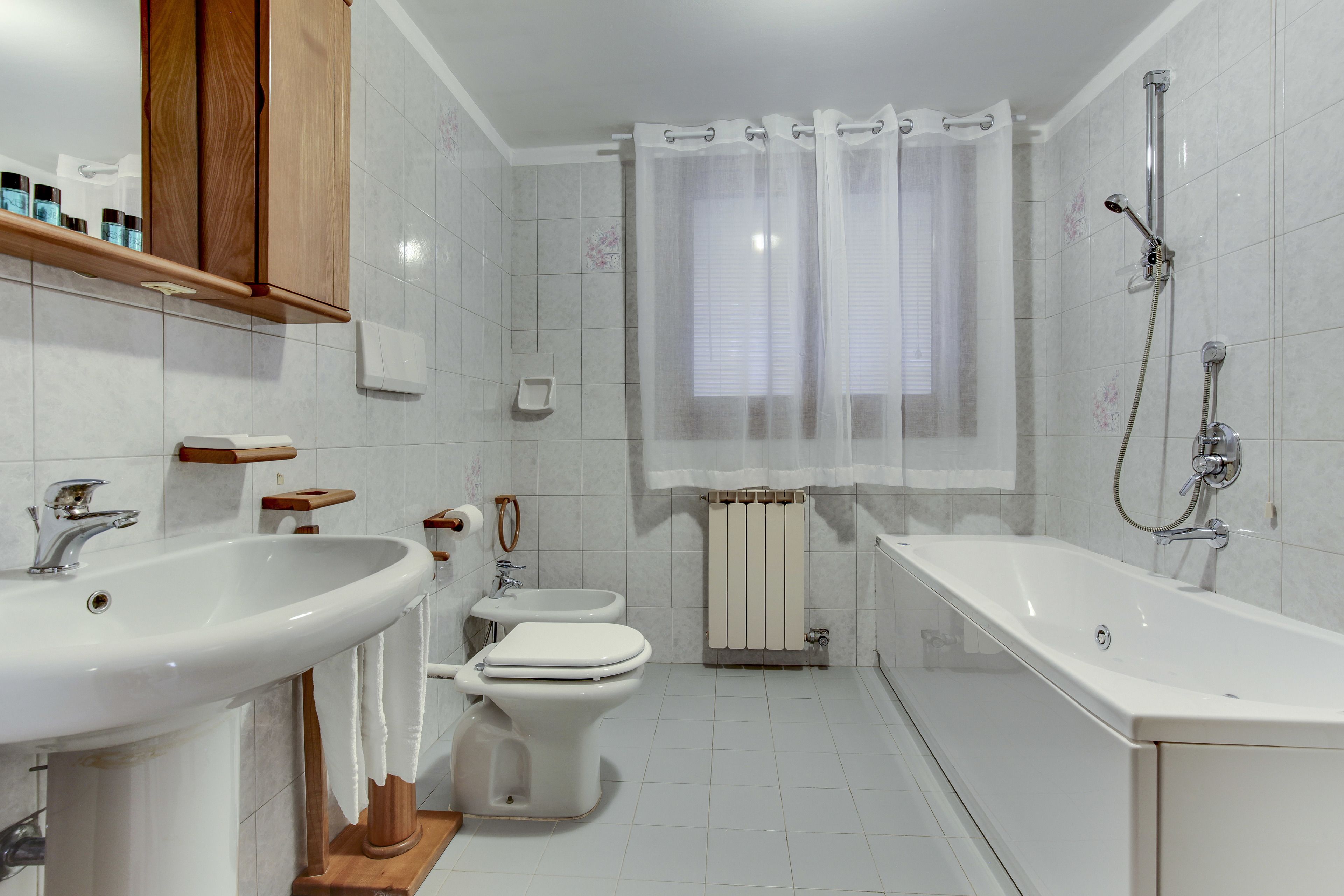 Een moderne badkamer met een wastafel, toilet, bidet en bad.
