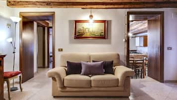 Una sala de estar acogedora con un sofá color beige, dos cojines, un cuadro enmarcado en la pared y techo de madera.