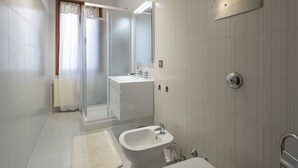 A modern bathroom with a glass shower, a sink, and a toilet. - Coco (Venice)