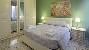 A bedroom with a bed, two bedside tables with lamps, a wardrobe, and a painting on the wall. - Coco (Venice)
