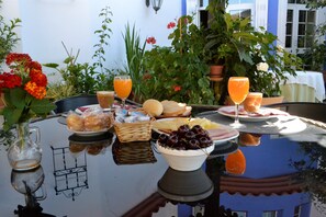 Una mesa dispuesta con comida y bebidas, rodeada de plantas y flores en macetas.