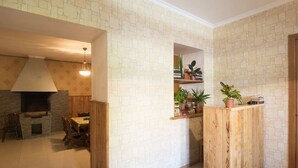 A room with a stone wall, a wooden table with chairs, a built-in shelf with plants, and a wooden counter. - Magdalena's House (Mtskheta)