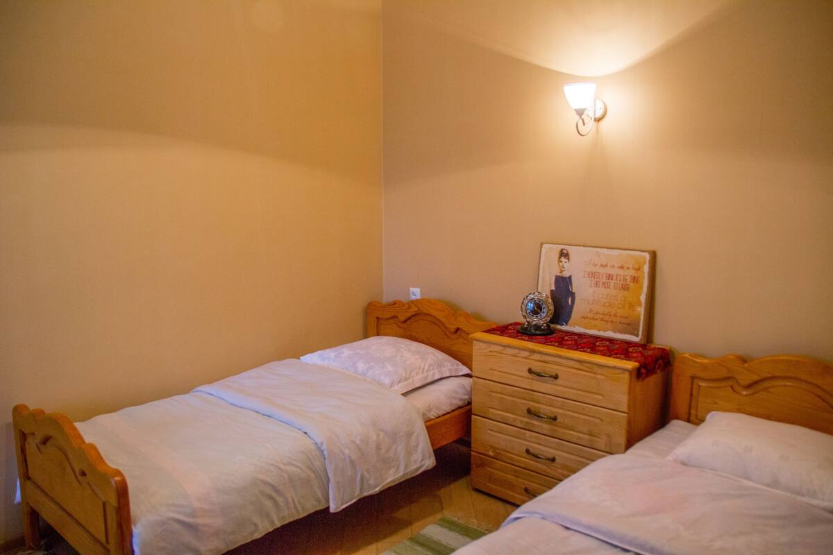 Un dormitorio con dos camas individuales, un aparador de madera y una lámpara de pared.