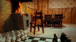 A room with a fireplace, wooden walls, a checkered floor, and a chessboard. - Magdalena's House (Mtskheta)