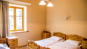 A bedroom with two beds, wooden headboards, a nightstand, a dresser, and a window with curtains. - Magdalena's House (Mtskheta)