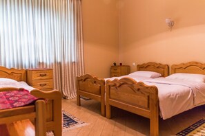 Un dormitorio con dos camas de madera, una mesita de noche, una pequeña mesa y una ventana con cortinas.