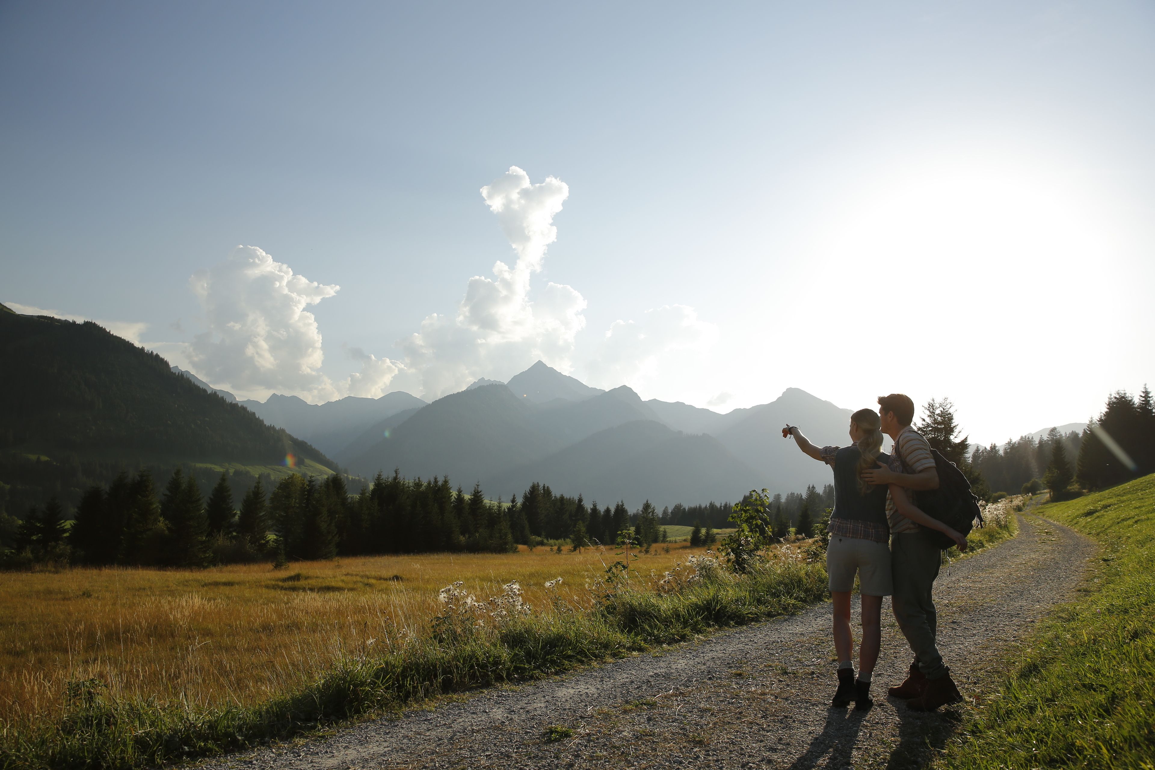 A couple on a gravel path with a mountainous landscape in the background.