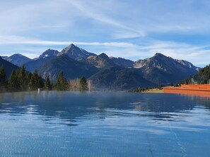 On distingue clairement une chaîne de montagnes, avec une grande étendue d’eau au premier plan, probablement un lac ou une mare, et une construction sur le côté droit.