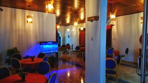 Un restaurant avec des tables rondes, des chaises et un aquarium.