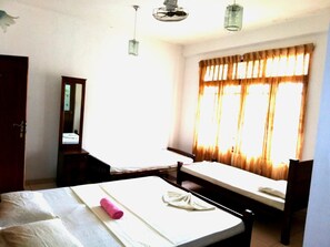 A hotel room with a bed, a chair, a desk, a mirror, and a window with curtains. - Hotel Elephant Lobby (Rambukkana)