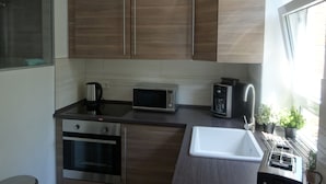 Una cocina moderna con armarios de madera, microondas integrado, horno y lavamanos.