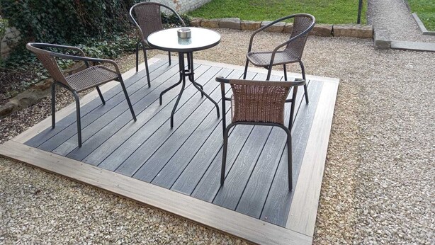 Un patio con una mesa redonda y cuatro sillas de mimbre.