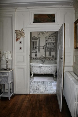 Une salle de bain avec une baignoire sur pieds, un miroir et un radiateur.