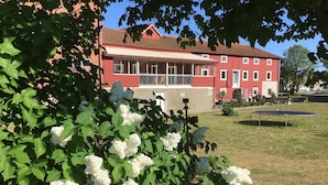A red building with a white porch and a grassy yard. - Borrby frö - Bed & Breakfast (Borrby)