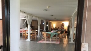A spacious dining area with high ceilings and a central table surrounded by chairs. - Borrby frö - Bed & Breakfast (Borrby)