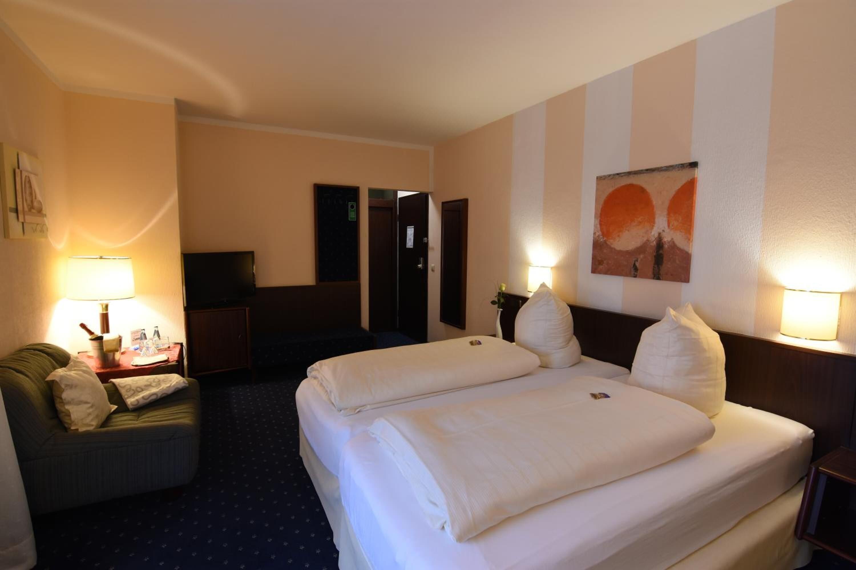 Ein Hotelzimmer mit zwei Betten, einem Schreibtisch, einem Stuhl und einem Fernseher.