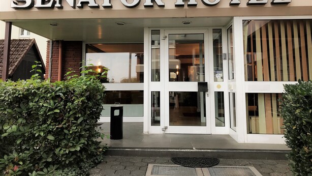 L’extérieur de l’hôtel Senator se caractérise par une entrée bien visible, un auvent en verre et une façade en briques.