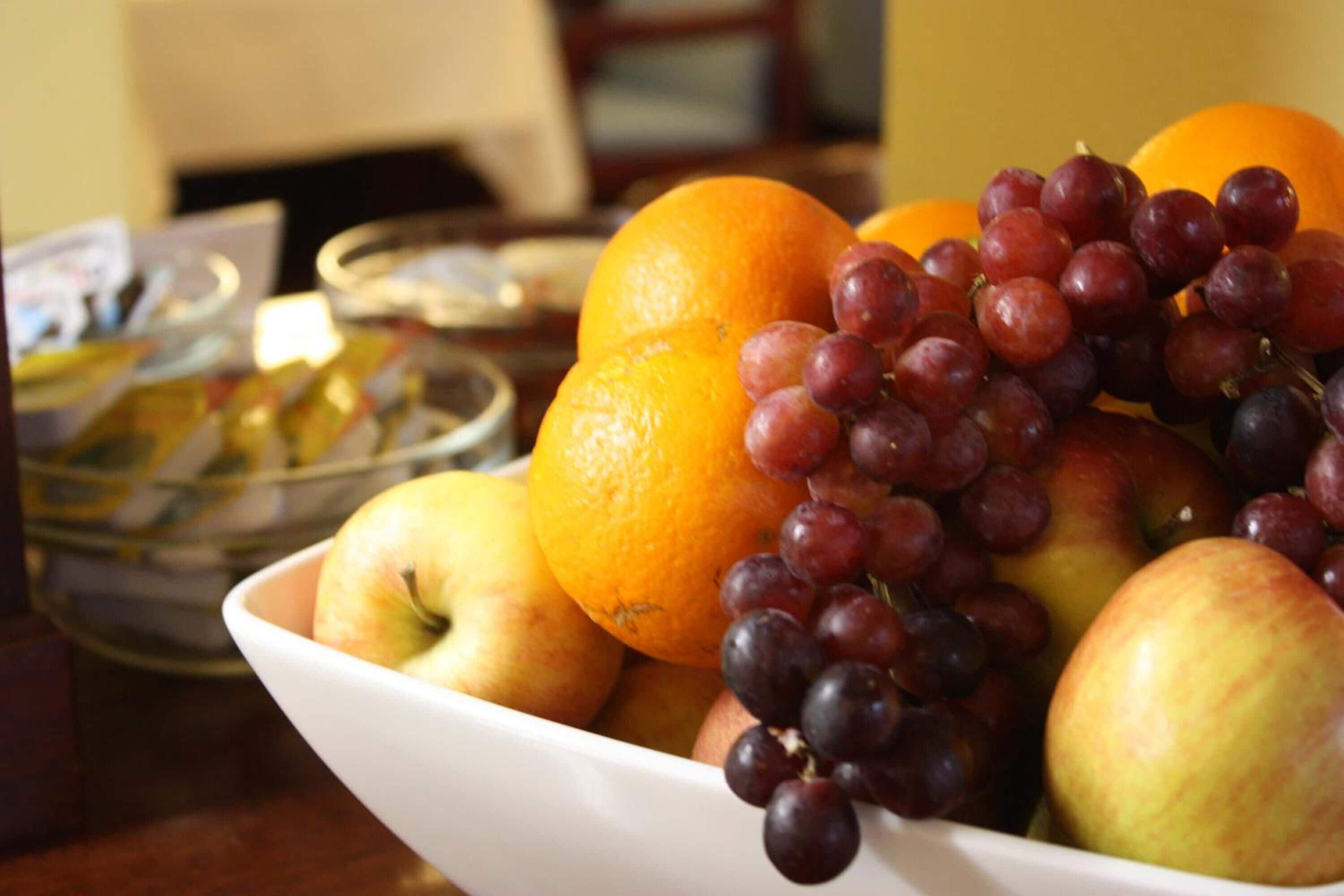 A bowl of fruit including apples, oranges, and grapes.