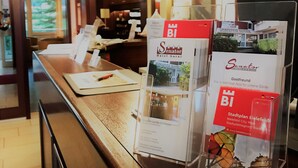 Un comptoir d’accueil d’hôtel avec des brochures d’information et un écran numérique.