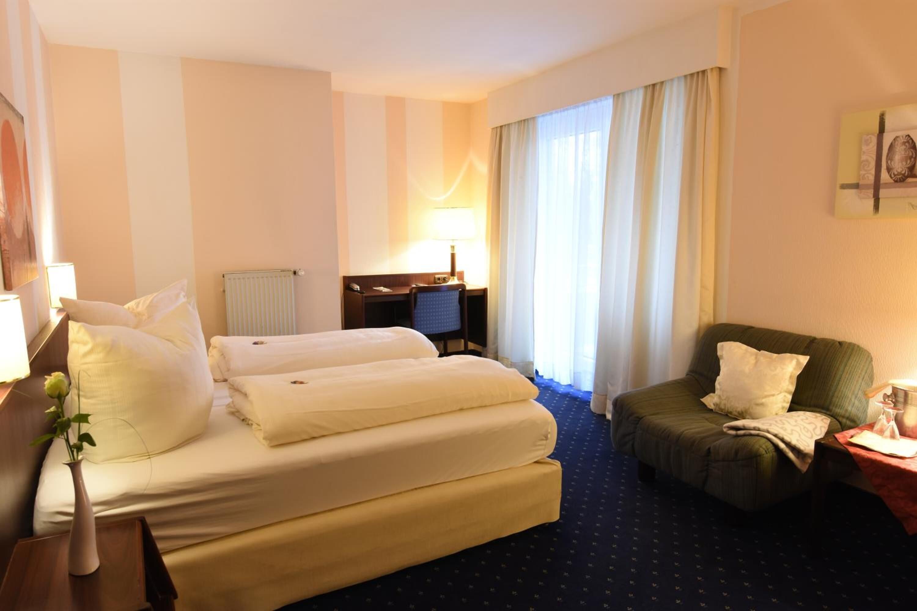 Une chambre d’hôtel avec un lit, un bureau, une chaise et un canapé.