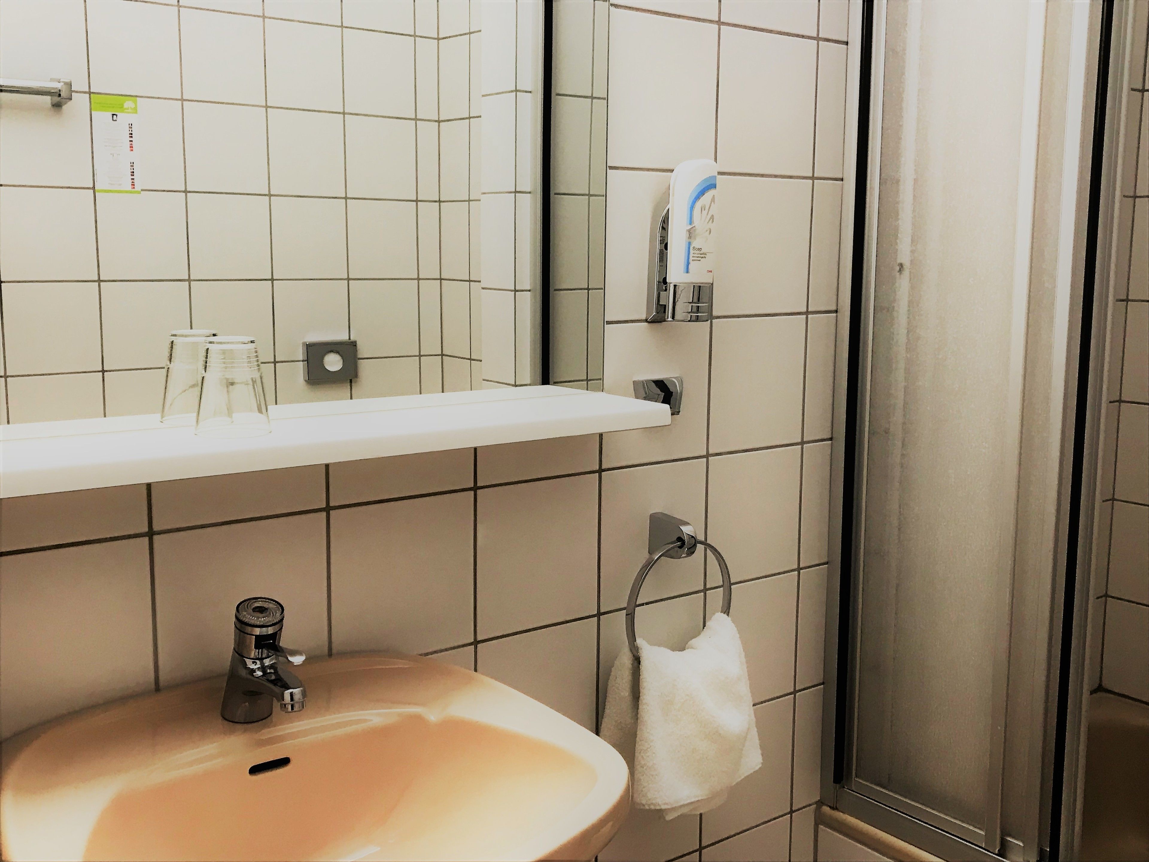 A bathroom with a sink, mirror, and towel rack.