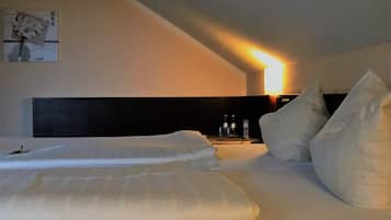 Et hotelværelse med en stor seng, et natbord og en lampe monteret på væggen.