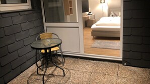 Une petite pièce avec une table et une chaise en verre, un lit et une armoire en bois.