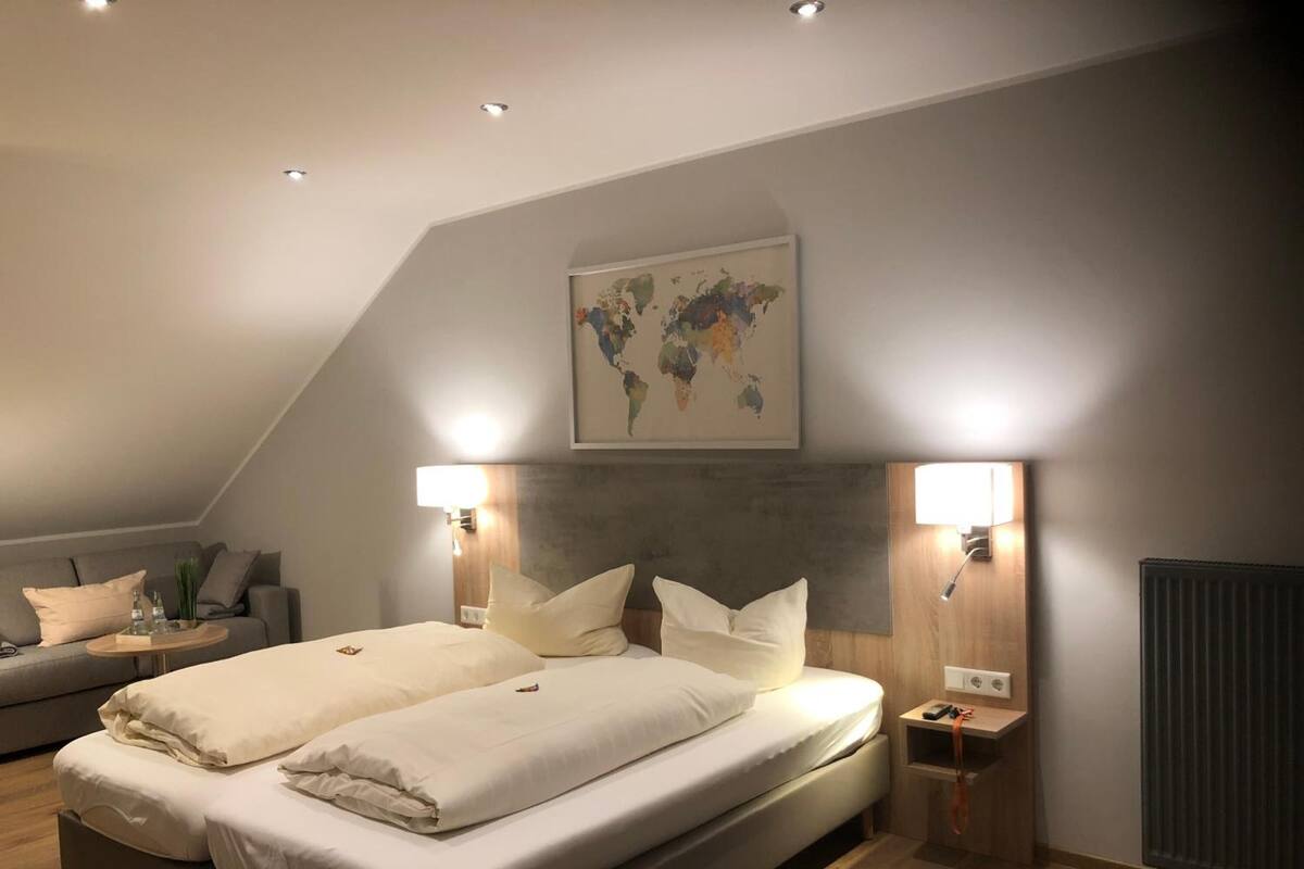 A modern bedroom with a large bed, two bedside tables, a world map on the wall, and a radiator.
