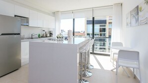 Una cocina moderna con una isla central, electrodomésticos de acero inoxidable y un amplio ventanal con vistas a la ciudad.