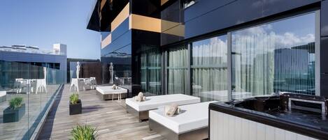 A rooftop terrace with outdoor seating, a hot tub, and a view of the city skyline.