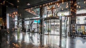 A spacious lobby with a polished marble floor, large glass doors, and modern lighting fixtures. - H Hotel (St. Julian's)