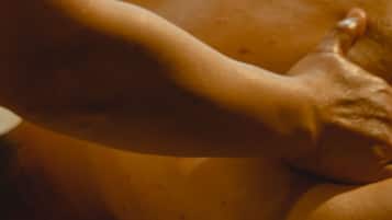 A close-up of a person's hand on a smooth, light-colored surface, possibly a bed or couch.