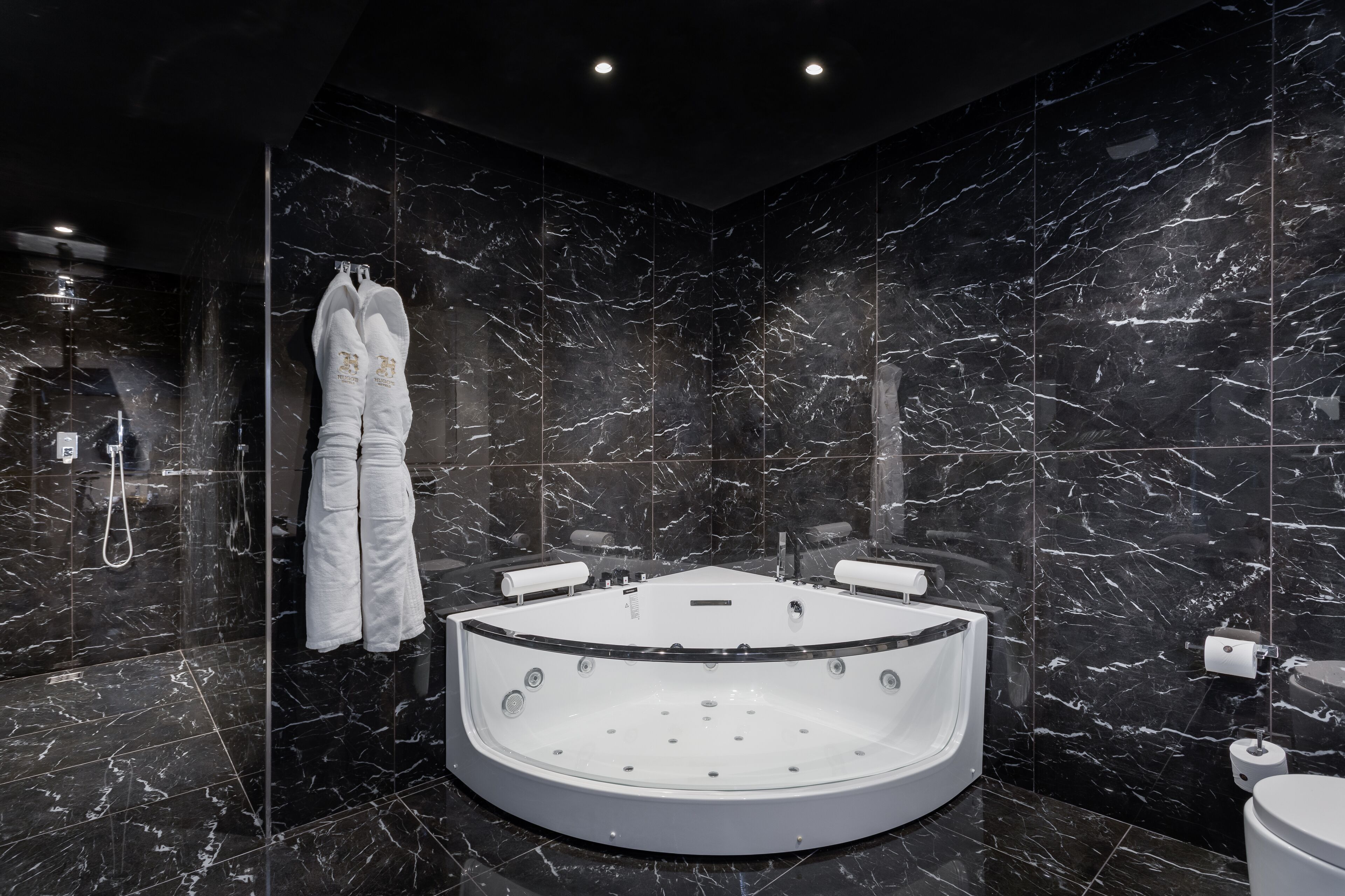 Een moderne badkamer met een vrijstaand bad, marmeren wanden en een handdoekhouder.