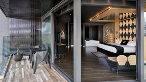 A modern hotel lobby with a glass partition, a seating area with a sofa and chairs, and a large potted plant. - H Hotel (St. Julian's)