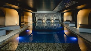 A modern spa with a central pool, seating areas, and a patterned ceiling. - H Hotel (St. Julian's)