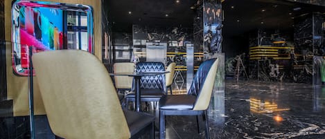 A modern interior with black marble floors, leather and metal furniture, and a large digital screen displaying colorful content.