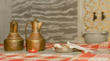 A bathroom with a marble wall, a toilet, and two brass containers on a checkered cloth.