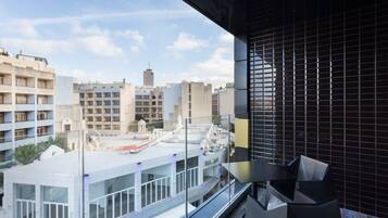 Ein moderner Hotelbalkon mit Blick auf umliegende Gebäude und einen klaren Himmel.