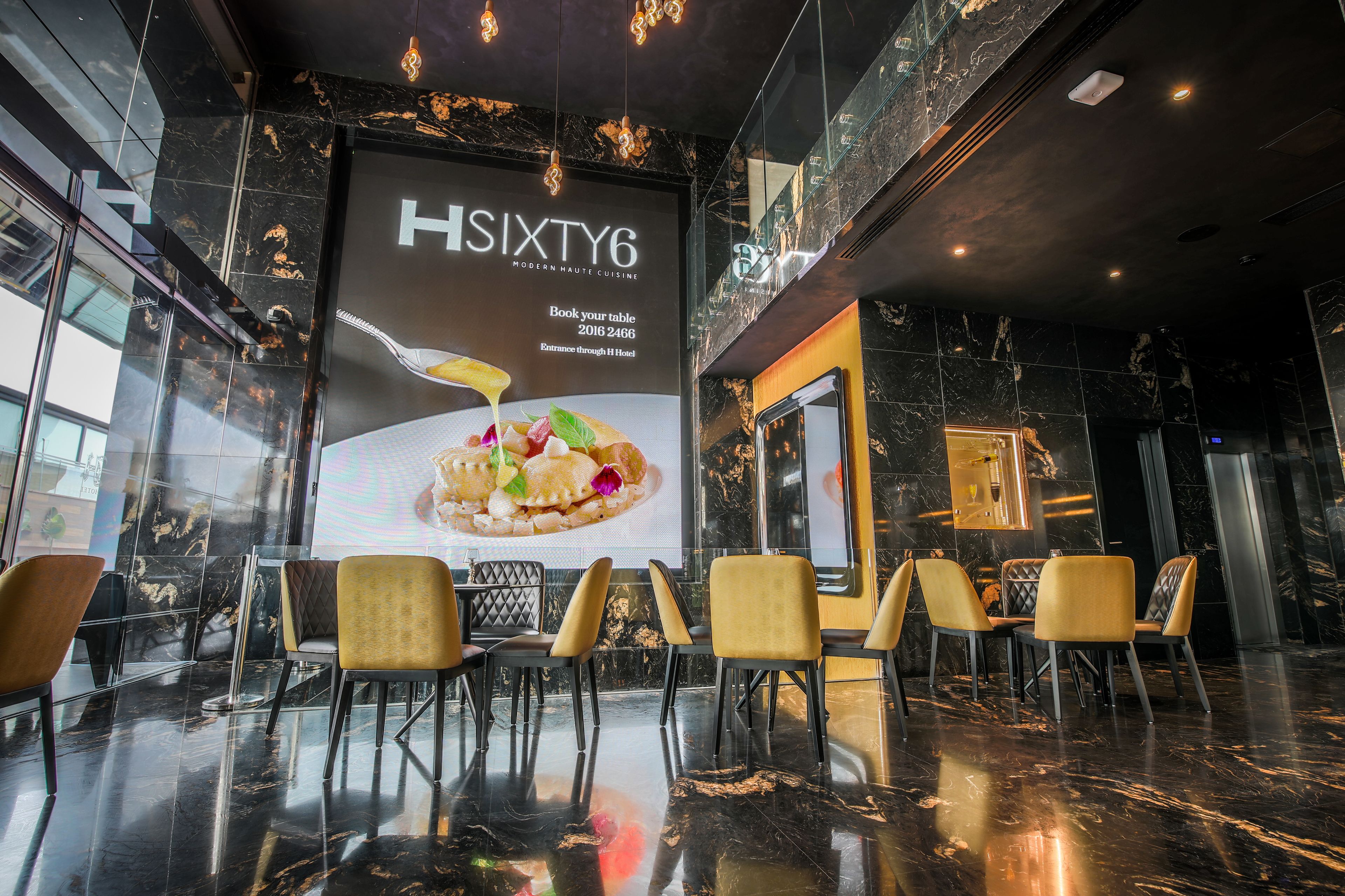 A modern restaurant interior with marble flooring, yellow chairs, and a large poster advertising 'HSIxty6 Modern Haute Cuisine'.