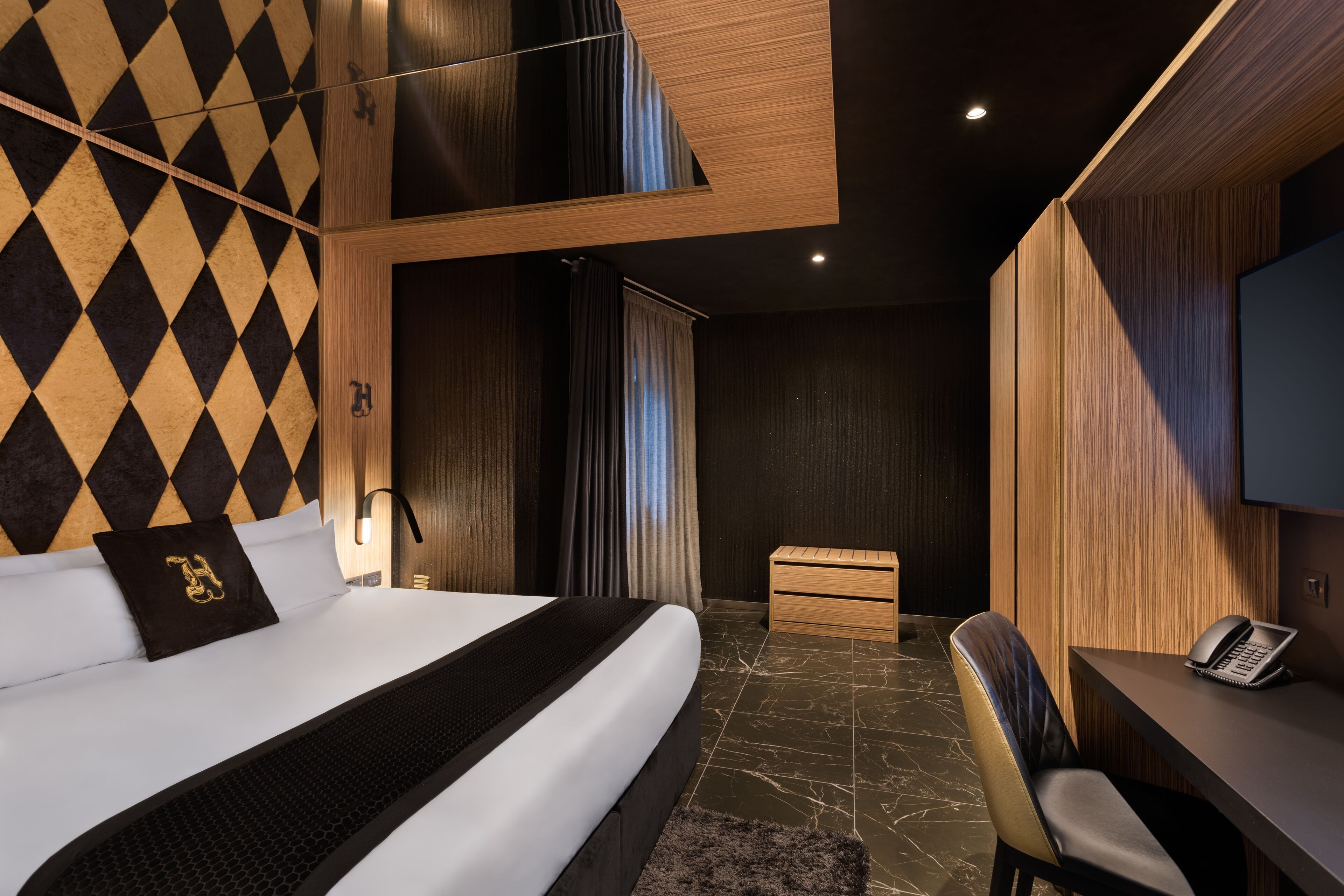 A modern hotel room with a large bed, a desk, and a television.