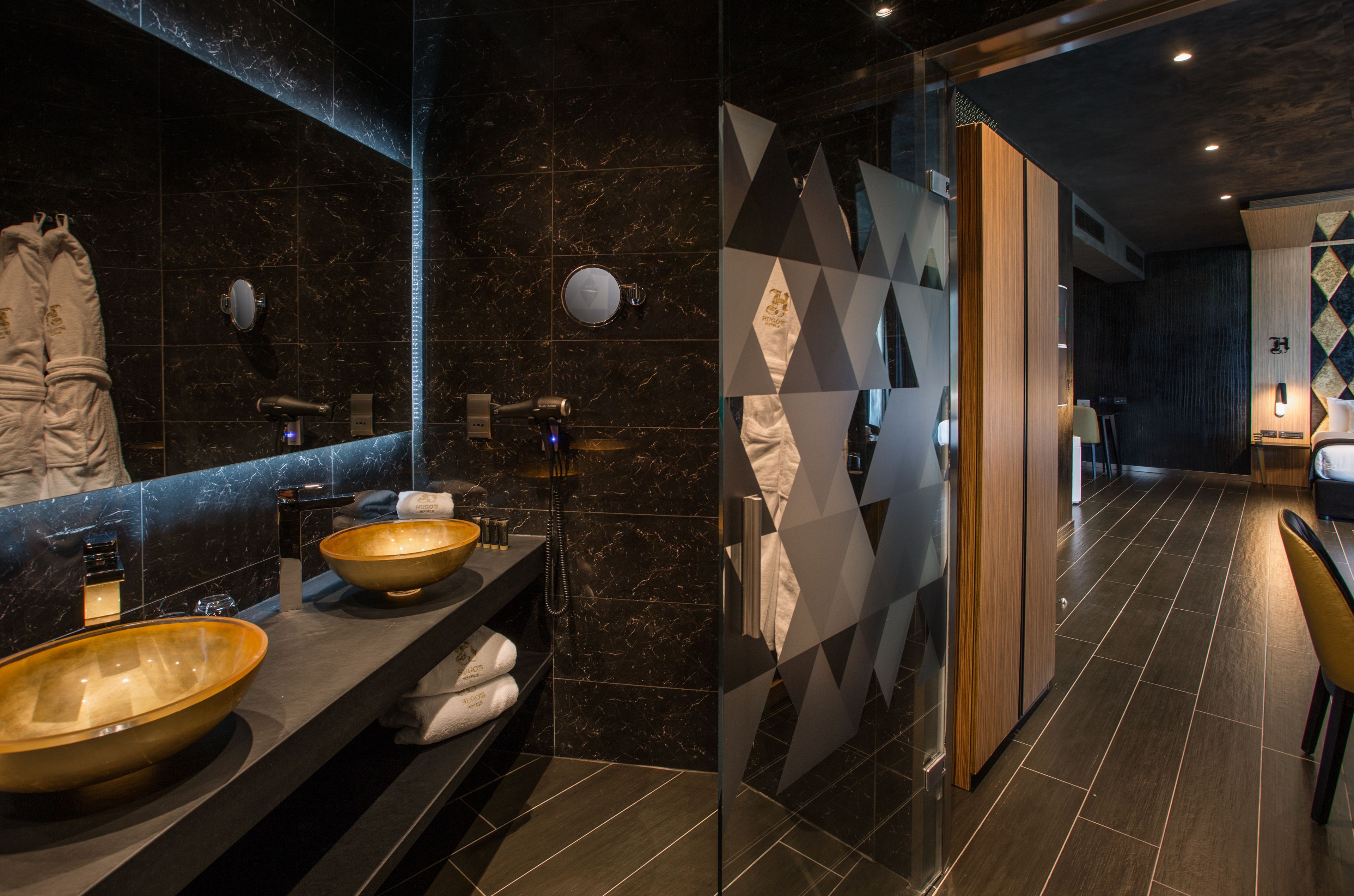 A modern bathroom with a large mirror, two sinks with a bowl-shaped basin, a towel rack, and a shower area.