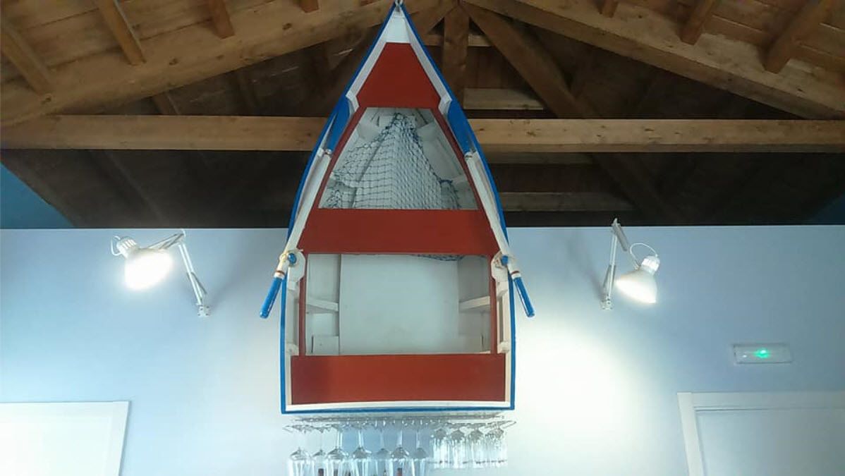 A room with a wooden ceiling, a red and blue triangular window, and two wall-mounted lamps.