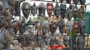 A collection of wooden masks hanging in a display case.