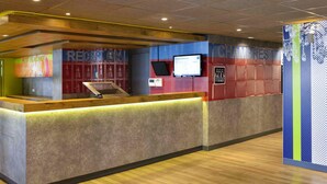 Un mostrador de recepción con pantalla digital, detalles de madera y paredes con diseño.