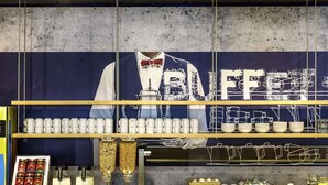 Una barra de bufet con un cartel grande que dice "BUFFET" y varios alimentos expuestos en estantes.