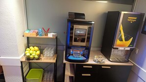 Eine Kaffeemaschine, ein Getränkeautomat und eine Obstauslage in einem Hotel.