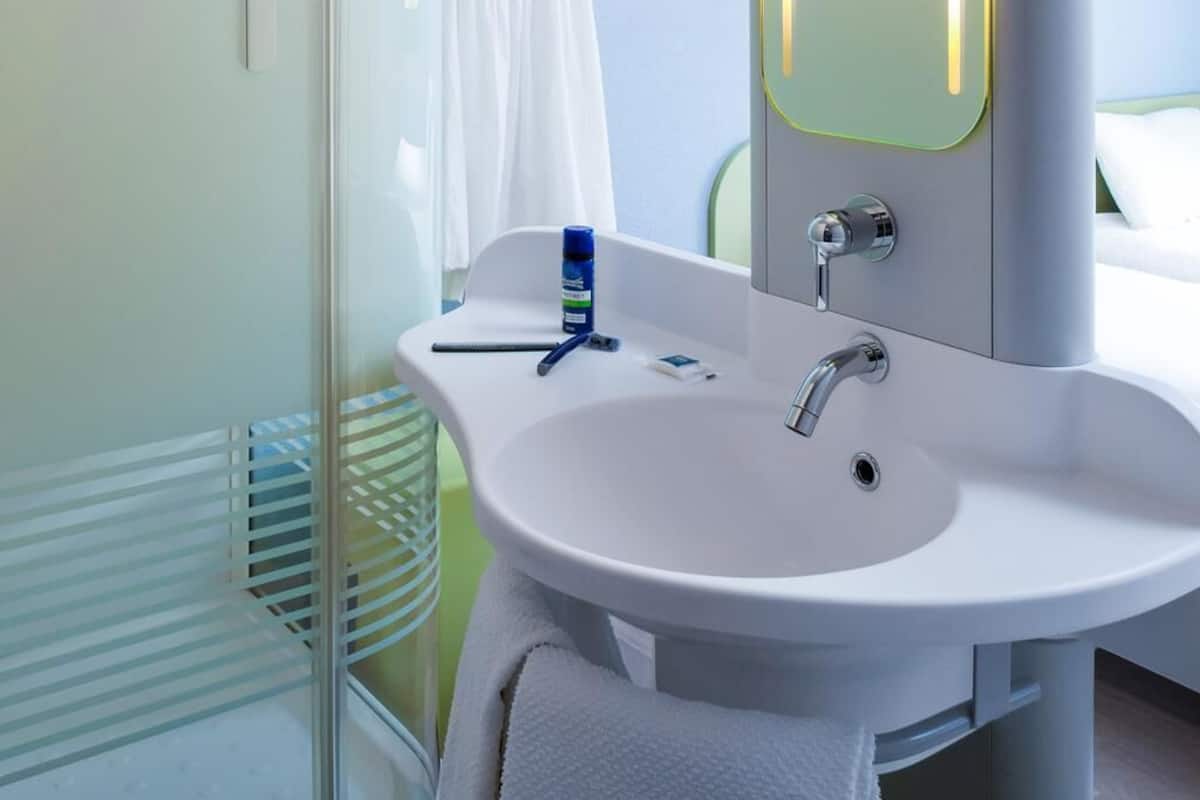 A bathroom with a white sink, a mirror, and a towel rack.