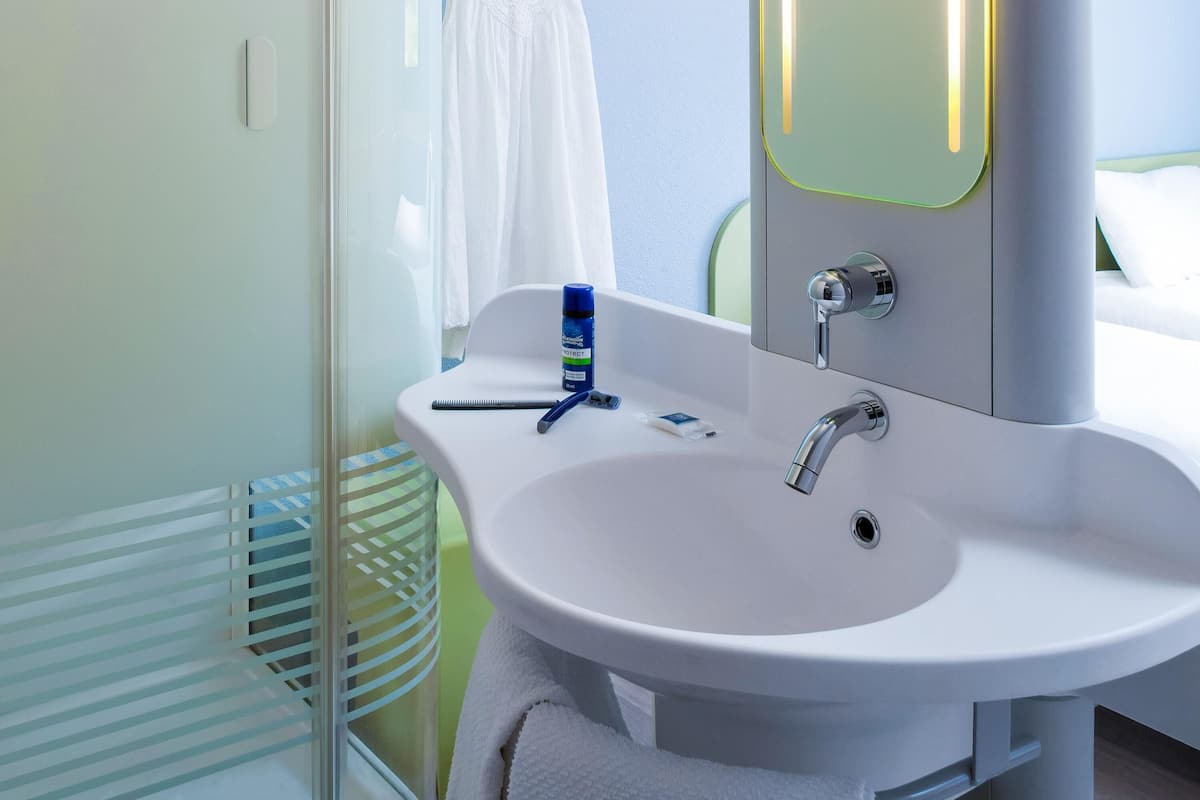 Un baño con lavamanos blanco, espejo y cortina de ducha.