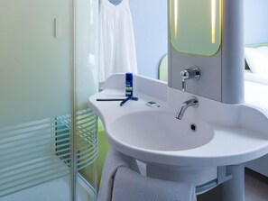 Un baño con lavamanos blanco, espejo y cortina de ducha.
